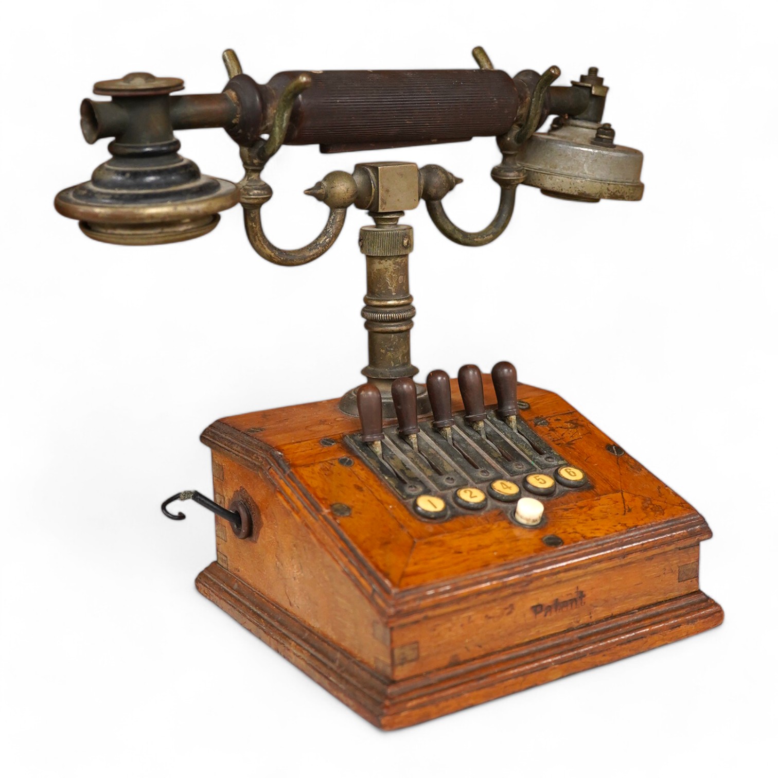 An early 20th century mahogany cased telephone, possibly by Ericsson, with handset on decorative cradle and five switchboard selector levers, stamped ‘Patent’ to front of the case, and with paper label underneath reading